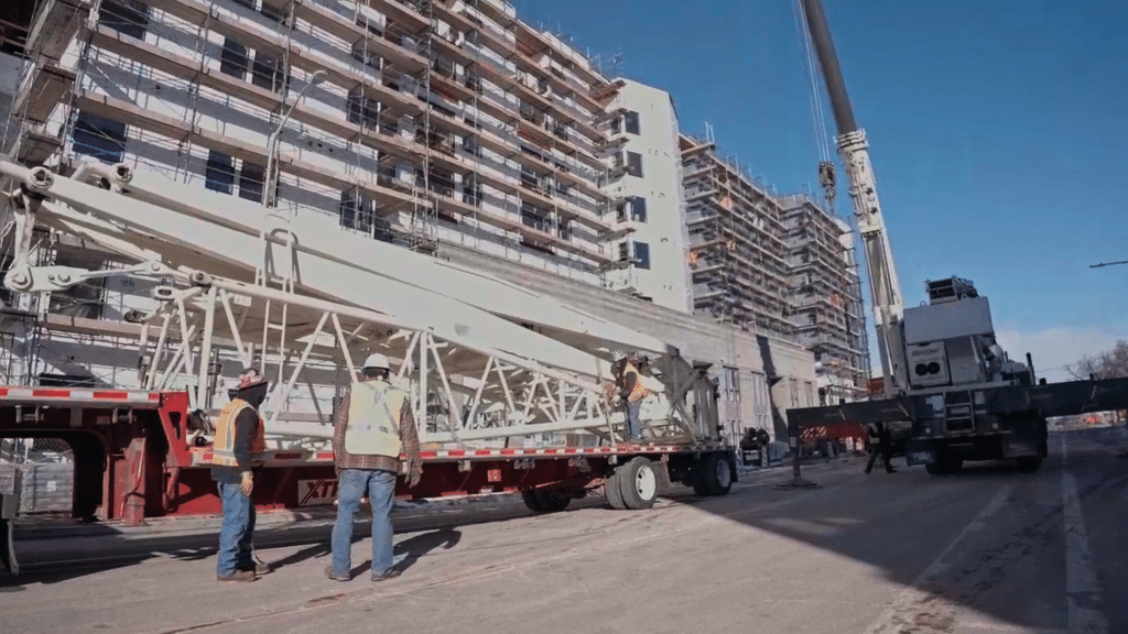 Heavy machinery in front of a multi-family building with scaffolding along the walls