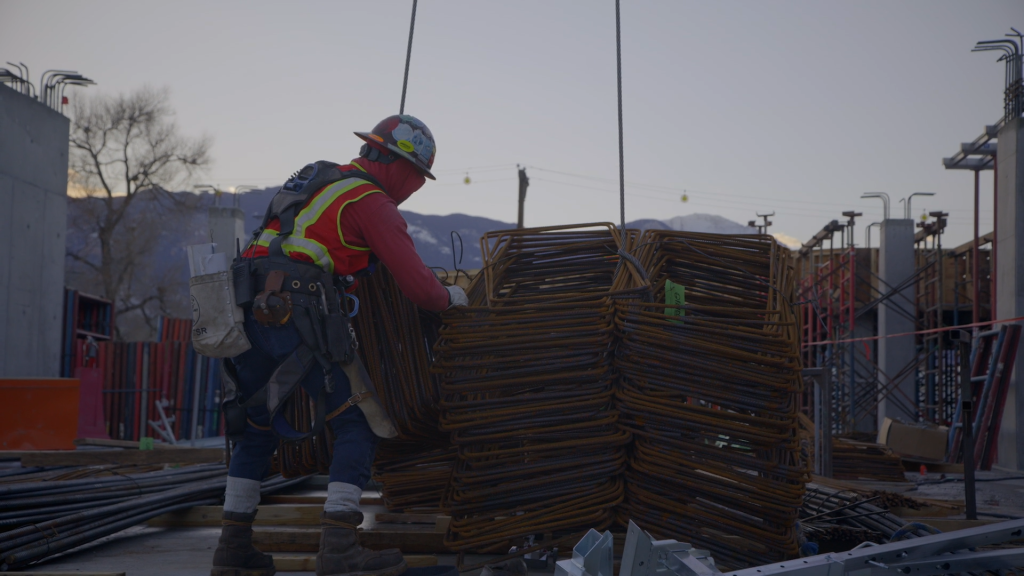 Worker moving metal bars with a pulley
